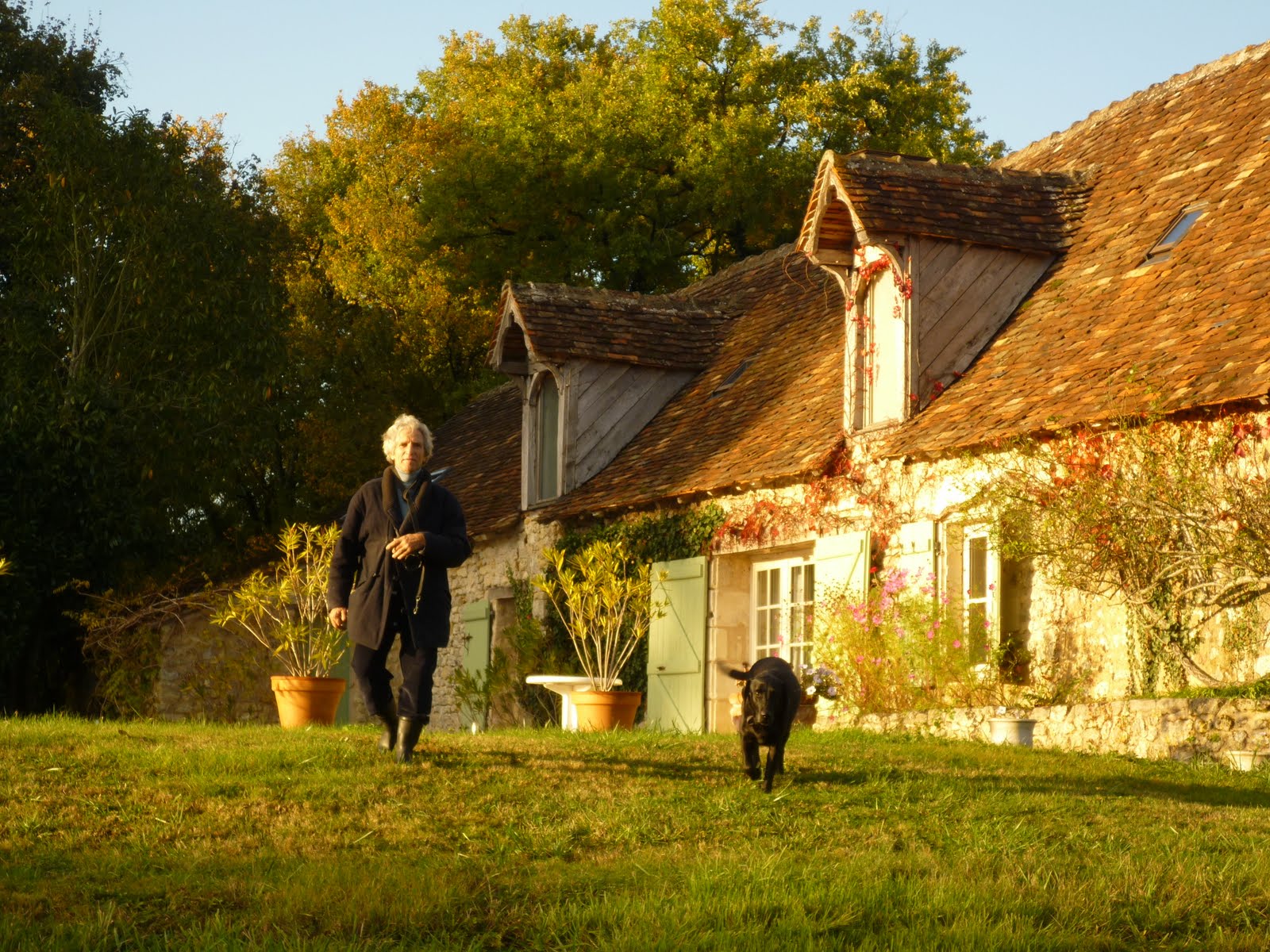 Eric Chauche et son chien devant la longère en pierre au coucher de soleil
